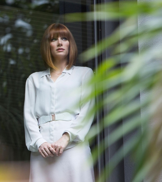 Claire_standing_near_plant_in_white_dress_looking_out_over_paddock.jpg